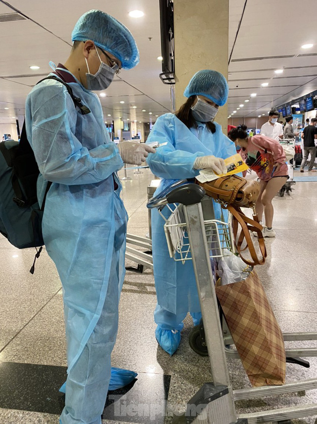 Hành khách mặc áo mưa, bảo hộ kín mít khi đi máy bay tại Tân Sơn Nhất - Ảnh 1.