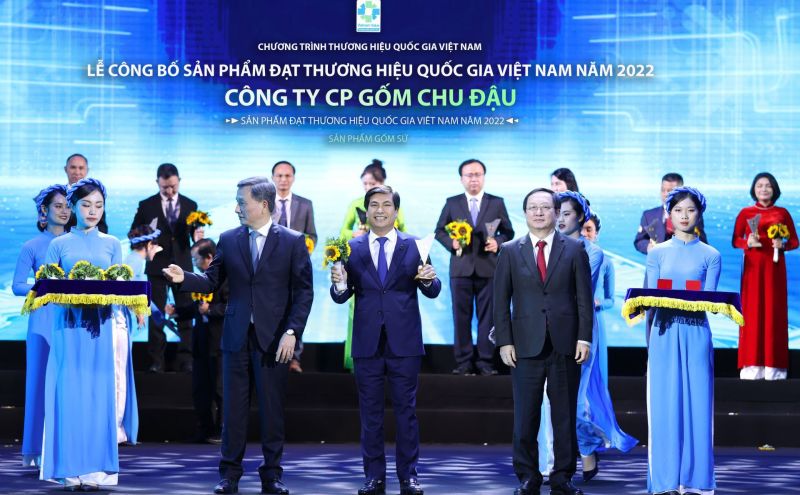Ông Nguyễn Hữu Thức (đứng giữa), Tổng Giám đốc Công ty CP Gốm Chu Đậu nhận hoa chúc mừng và biểu trưng Thương hiệu quốc gia Việt Nam